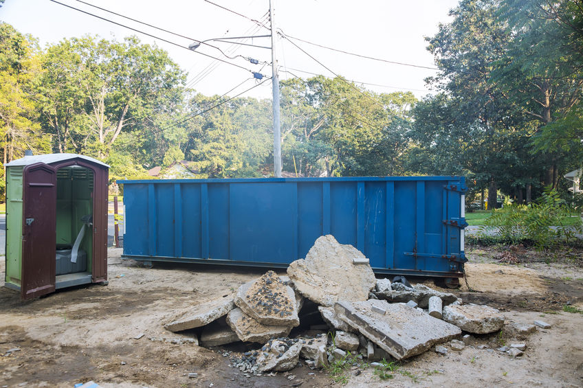 Removal of debris construction waste building demolition with rock and concrete rubble on portable bio toilet cabins at the construction site