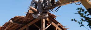 An industrial excavator tearing down the framework of an old roof corner